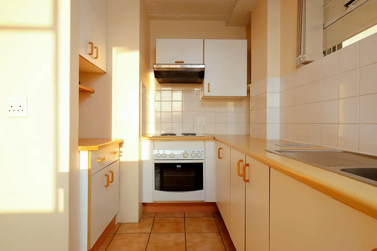 A kitchen with white cabinets and tile floors.